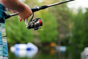 Close-up of a hand holding a fishing rod over the water