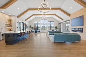 Bright event or clubhouse space with vaulted ceiling, chandelier, hardwood floors, and large windows